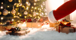 Santa Claus carries Christmas presents under the tre